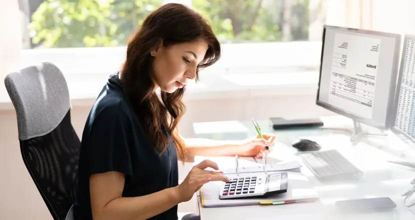 Accountant with a bachelor's degree seated at desk calculating balances