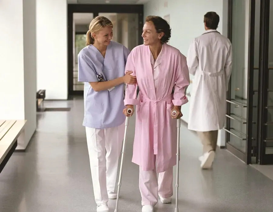 Occupational therapist helping patient walk on crutches